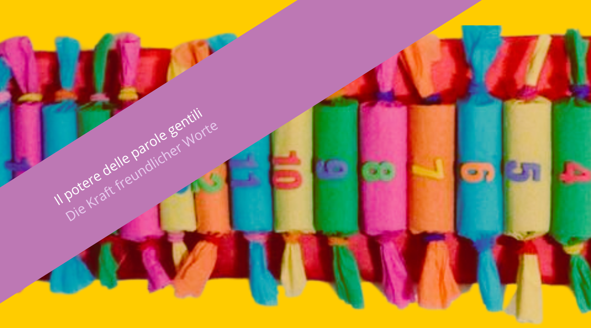 Auf dem Bild ist ein Kalender zu sehen, der aus kleinen, farbigen und nummerierten zylinderförmigen Päckchen besteht. Der Hintergrund ist gelb. Über dem Bild ist ein violetter Streifen mit der Aufschrift „Il potere delle parole gentili. Die Kraft freundlicher Worte“ zu sehen.