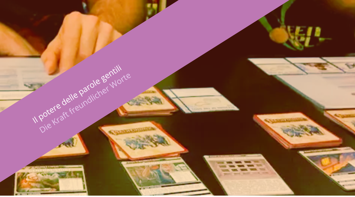 Auf dem Bild ist ein Tisch mit Spielkarten und eine Hand zu sehen, die diese aufdeckt. Über dem Bild ist ein violetter Schriftzug mit der Aufschrift „Il potere delle parole gentili. Die Kraft freundlicher Worte“ zu sehen.