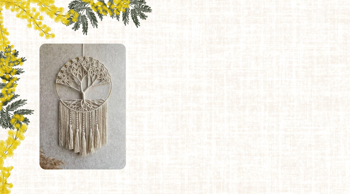 Ein aus Makramee gefertigter Lebensbaum ist von blühenden Mimosenzweigen umgeben. Der Hintergrund ist in Naturstofffarbe gehalten.